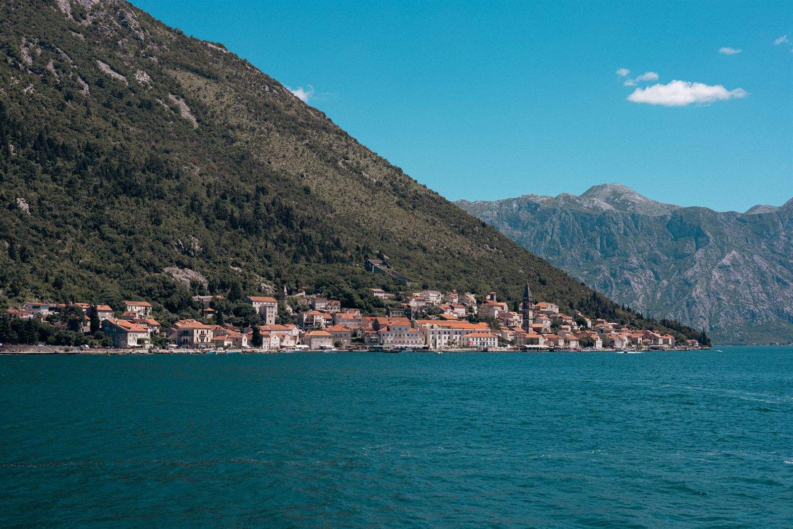 Small stone village on the shore of a deep bay between steep mountains