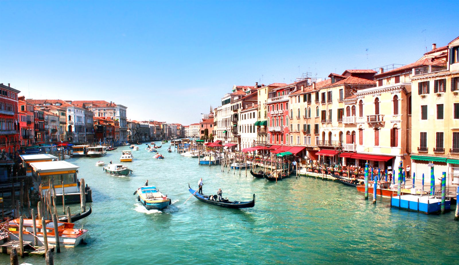 Boats and gondolas on the Grand Canal in Venice between colorful palazzi